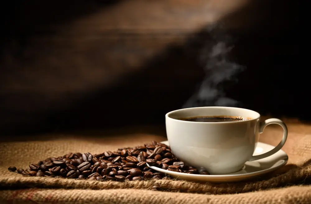 hot coffee on a table with roasted beans on the side