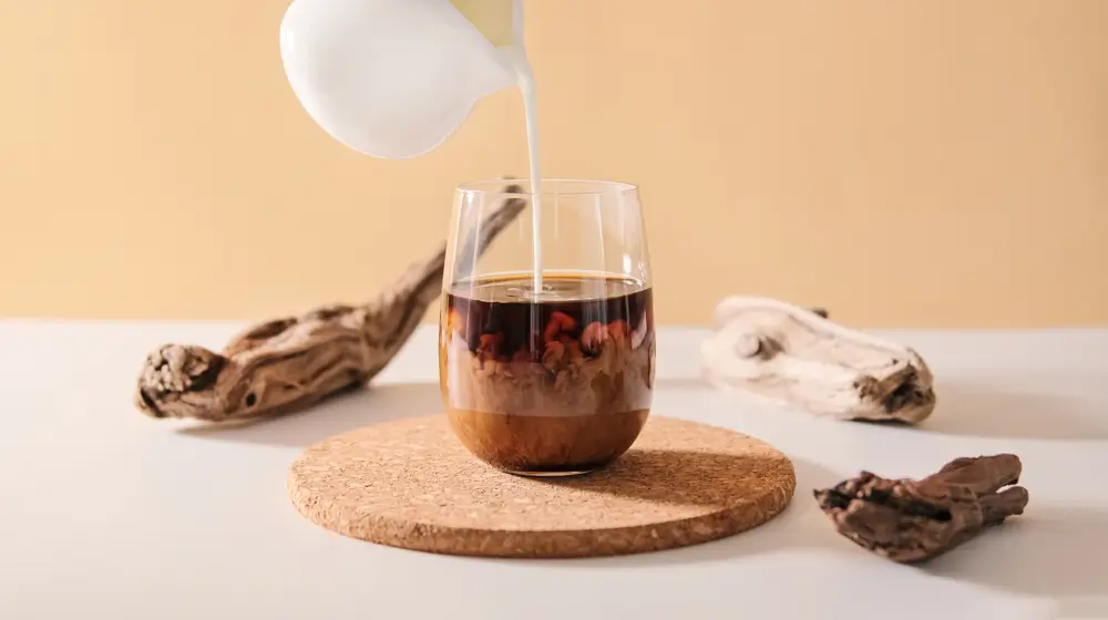 a beautiful shot of creamer being poured in a glass of coffee