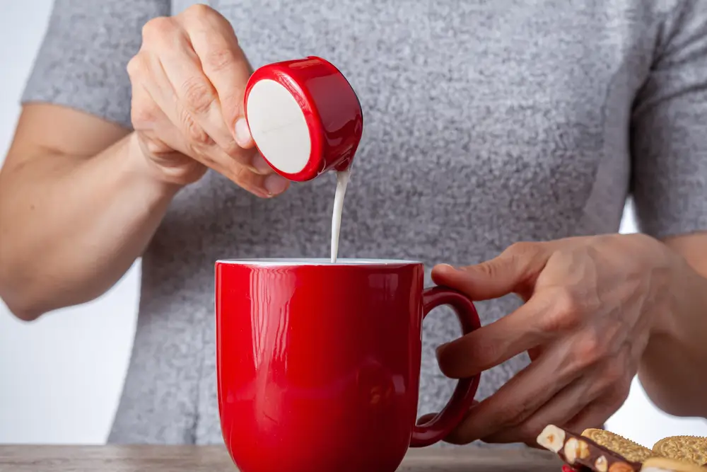 a man pouring creamer in a cup of coffee