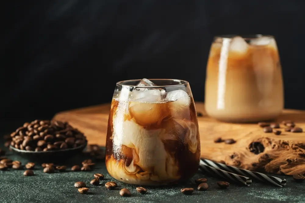 a glass of iced coffee placed on a dark kitchen  counter with dark lighting