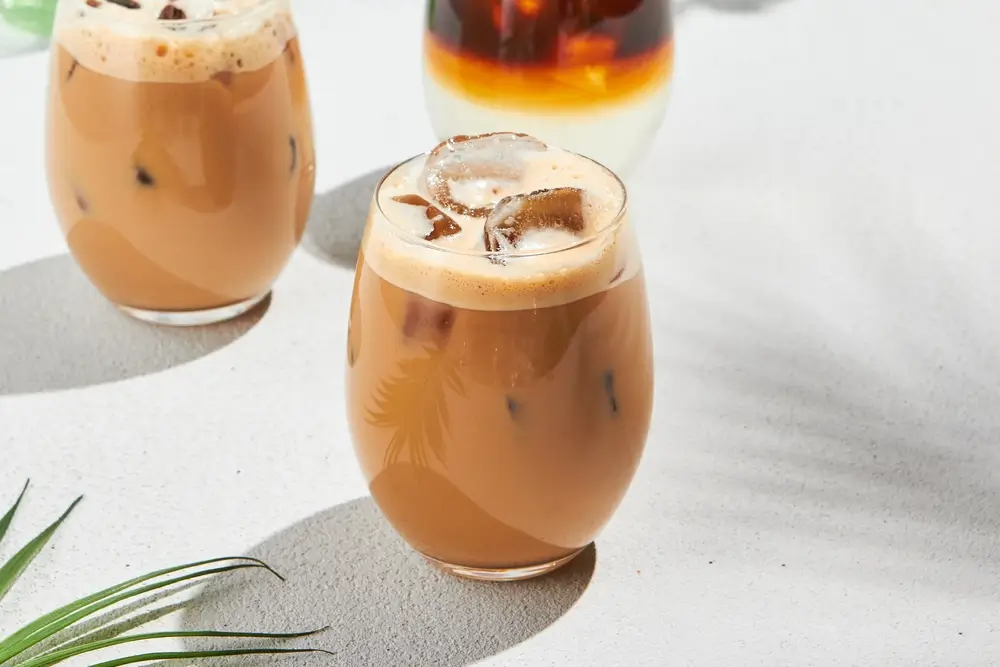 a glass of iced coffee made at home placed on a white marble kitchen counter